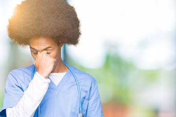 Young african american doctor man with afro hair tired rubbing nose and eyes feeling fatigue and headache. Stress and frustration concept.