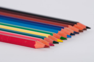 Fototapeta premium Many colored pencils on a white background close-up, macro, side view, with space for text.