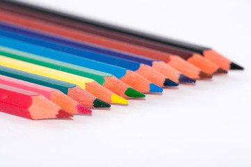 Fototapeta premium Many colored pencils on a white background close-up, macro, side view, with space for text.
