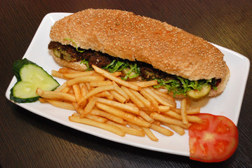 falafel sandwich with French fries and vegetables on the white plate