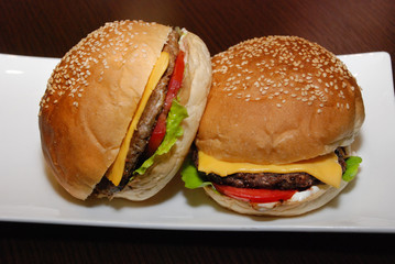 Two burgers with cutlet and cheese on the white plate