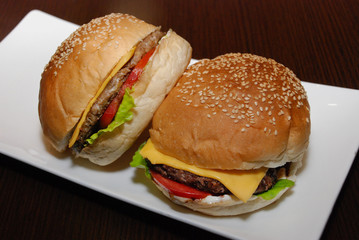 Two burgers with cutlet and cheese on the white plate
