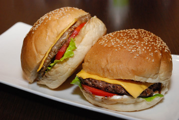Two burgers with cutlet and cheese on the white plate