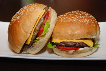 Two burgers with cutlet and cheese on the white plate