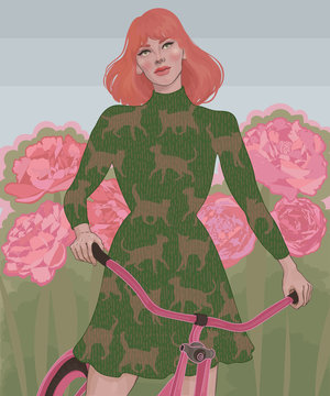 Red-haired girl in a dress riding a bike among a blooming garden