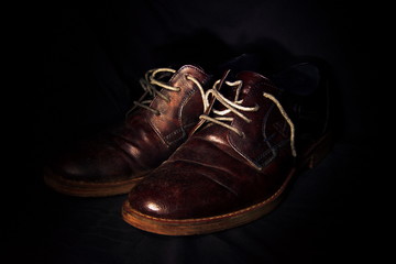 un paio di vecchie scarpe viste in primo piano, sfondo nero