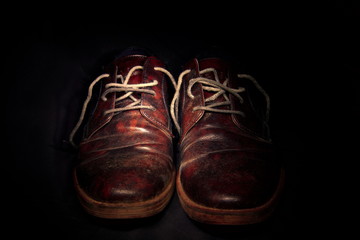 un paio di vecchie scarpe viste in primo piano, sfondo nero