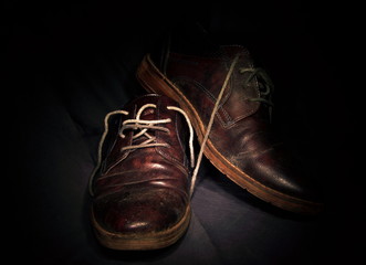 un paio di vecchie scarpe viste in primo piano, sfondo nero
