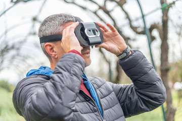 Man with VR visor in a park exploring surroundings. New technology and tourism concept