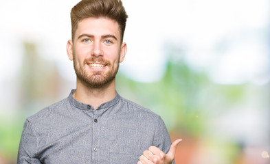 Young handsome business casual man doing happy thumbs up gesture with hand. Approving expression looking at the camera with showing success.
