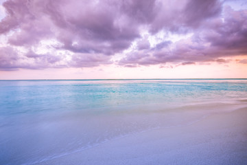 Obraz premium Beautiful morning, pink sunrise over sea, soft waves and calm sea under cloudy sky