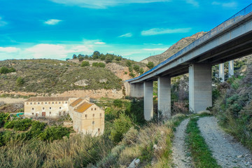 Nerja, Malaga, Andalusi, Spain - February 7, 2019: Old and abandoned farm in torrent under an elevated highway over the house