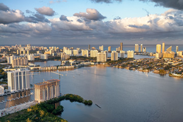 Sunset aerial view of Miami skyline from helicopter. Buildings, water and cloudy sky at dusk