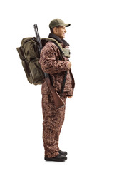 Hunter in a uniform standing with a backpack and shotgun on his shoulder