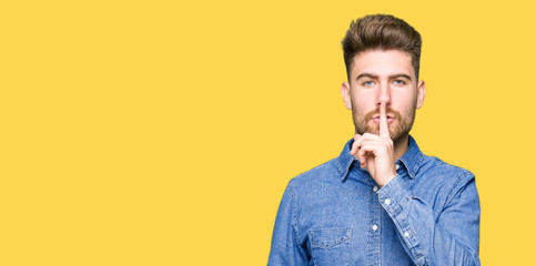 Fototapeta premium Young handsome blond man wearing casual denim shirt asking to be quiet with finger on lips. Silence and secret concept.