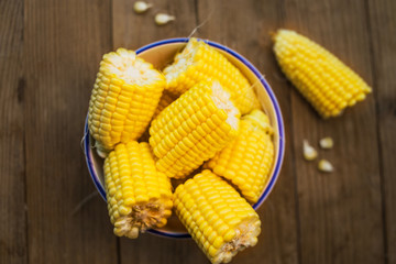 Fresh corn on cobs on rustic wooden table, closeup. Ripe corn. Half of broken open sweet corn