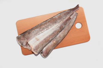 Frozen fish hake close-up on a wooden cutting board on a white background close-up
