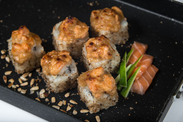 Japanese sushi rolls on a black frying pan. close view