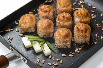 Japanese sushi rolls on a black frying pan. close view