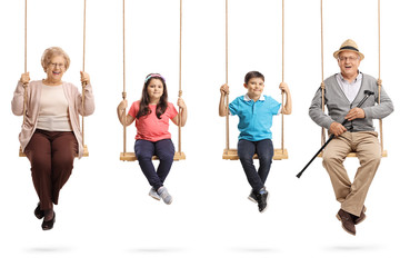 Grandparents and grandchildren on swings smiling at the camera