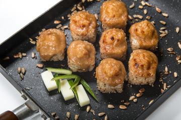 Japanese sushi rolls on a black frying pan. close view
