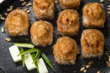 Japanese sushi rolls on a black frying pan. close view
