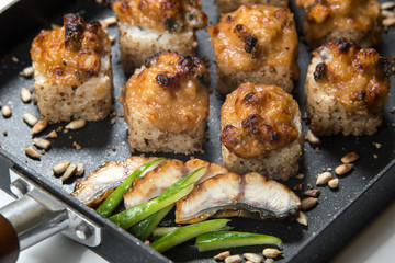 Japanese sushi rolls on a black frying pan. close view