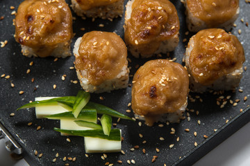 Japanese sushi rolls on a black frying pan. close view