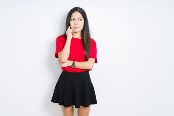 Beautiful brunette woman wearing red t-shirt and skirt over isolated background with hand on chin thinking about question, pensive expression. Smiling with thoughtful face. Doubt concept.