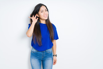 Beautiful brunette woman over isolated background smiling with hand over ear listening an hearing to rumor or gossip. Deafness concept.