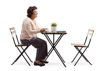 Senior woman sitting at a table drinking coffee