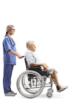 Young Female Nurse Pushing An Elderly Male Patient In A Wheelchair