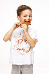 little messy boy is eating chocolate studio shot 