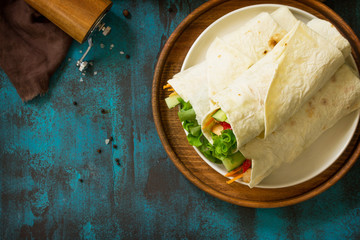 Healthy lunch snack. Tortilla wraps with grilled chicken and  fresh vegetables on blue table. Chicken Tortilla, mexican street fast food. Copy space, top view flat lay background.