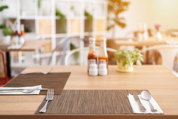 Close-up of luxurious spoon and fork, flower vaseson, sauce bottle the dining table decoration in hotel