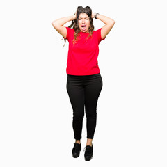 Fototapeta premium Young beautiful woman wearing casual t-shirt Crazy and scared with hands on head, afraid and surprised of shock with open mouth