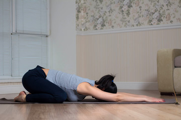 Young attractive woman practicing yoga, wearing sportswear, meditation session, home interior