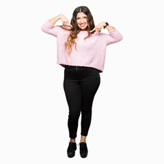 Young beautiful woman wearing pink sweater looking confident with smile on face, pointing oneself with fingers proud and happy.