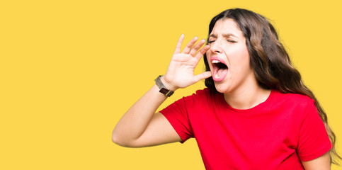 Young beautiful woman wearing casual t-shirt shouting and screaming loud to side with hand on mouth. Communication concept.