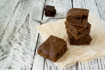 Chocolate Brownie on paper on white-brown rustic background with copy space