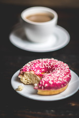 Bite a Pink donut with white sprinkle