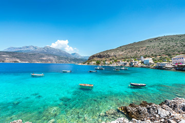 Small fishing boats on turqoise water of meditteranean bay. Landscape image of Greek sea village.