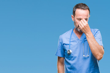 Middle age hoary senior doctor man wearing medical uniform over isolated background tired rubbing...