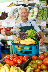 Owner of greengrocery with full shopping basket
