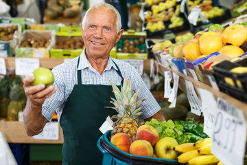 Elderly salesman working in greengrocery