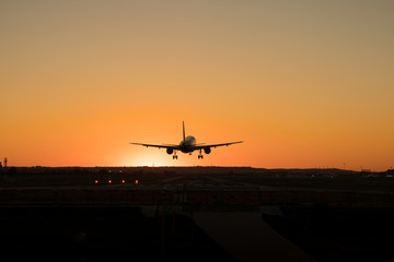 Fototapeta na wymiar Commercial airplane is landing on the airport runway during sunset.