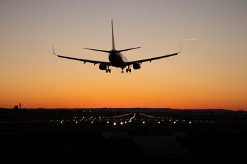 Fototapeta na wymiar Commercial passenger airplane is landing on the airport runway during sunset