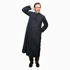 Middle age priest man wearing catholic robe Suffering of neck ache injury, touching neck with hand,...