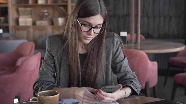 Two smart and presentable ladies who are groupmates work together on the mutual project/task on economy. They sit in the cafe, make notes and analyze the world population growth and income per capita.