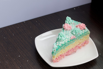 The piece is cut off and lies side by side on a saucer. Waffle cake made from cream soaked cakes. Decorated with cream flowers.